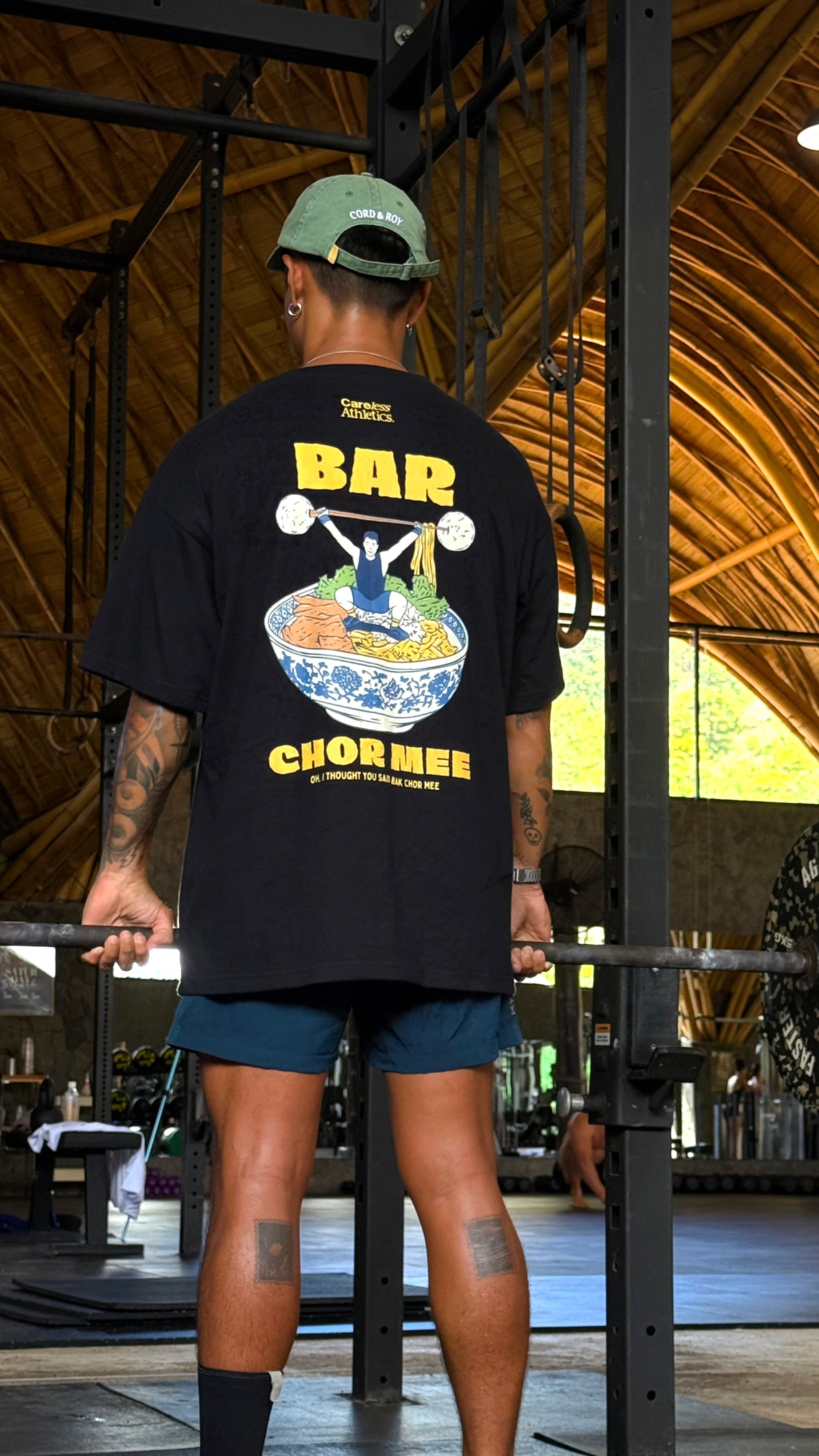 Person wearing a black t-shirt with a graphic design and text in a gym setting
