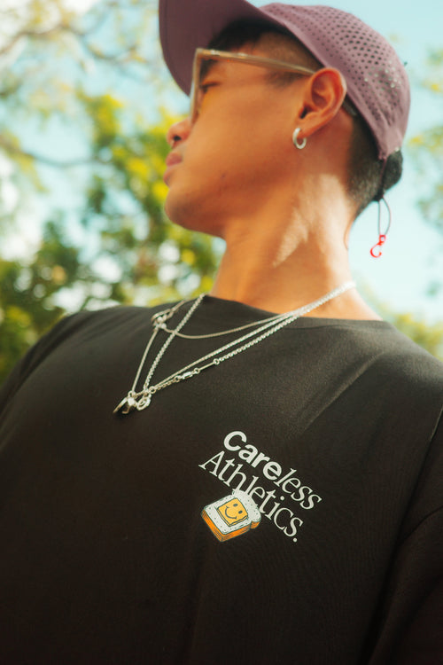 Person wearing a black t-shirt with 'Careless Athletics' logo, outdoors.