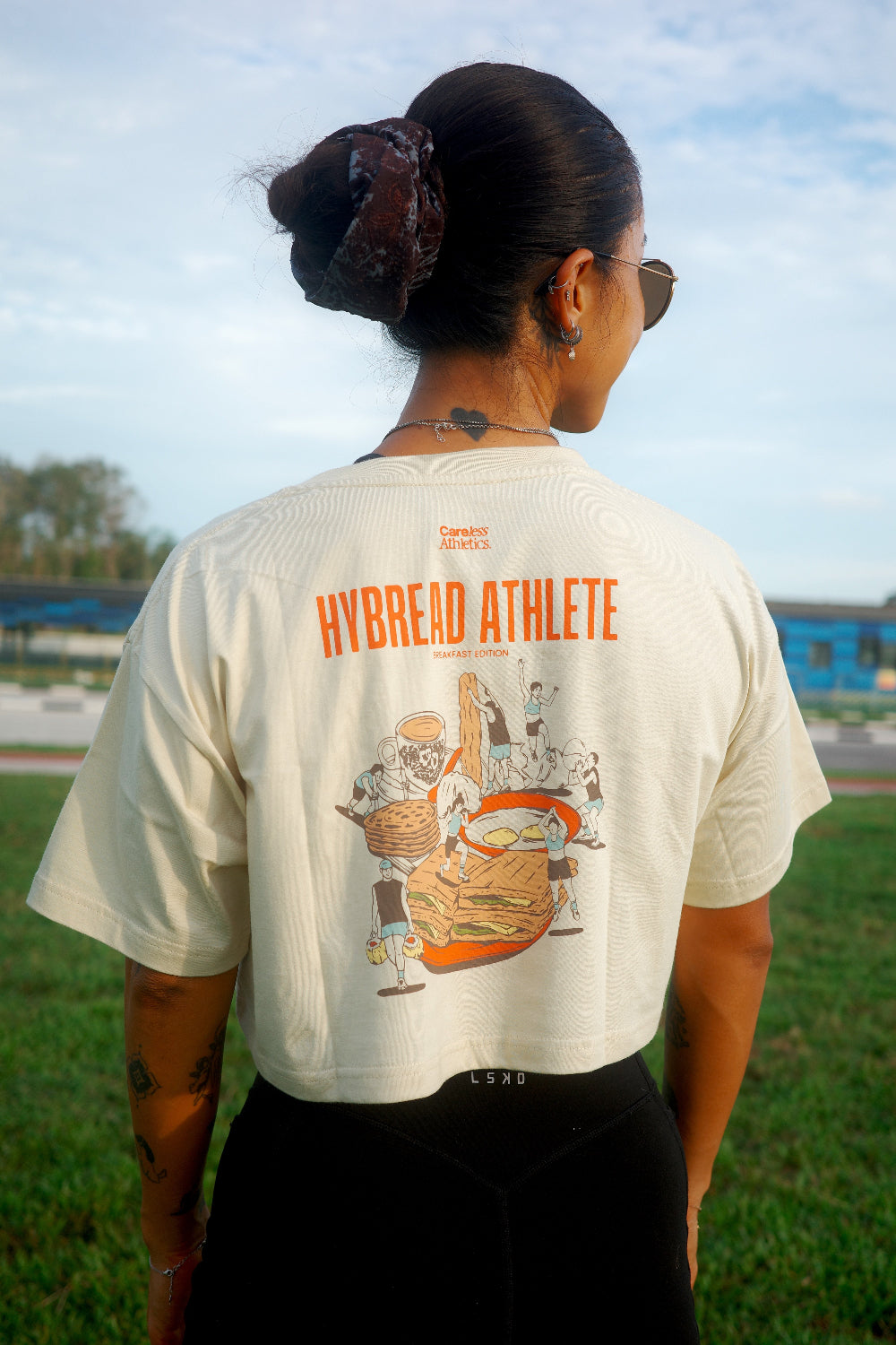 Person wearing a white t-shirt with a graphic design and text, standing outdoors.